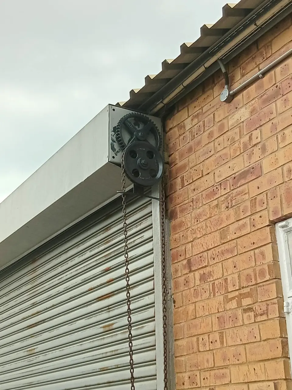 Chain-and-gear operating mechanism on a roller door barrel