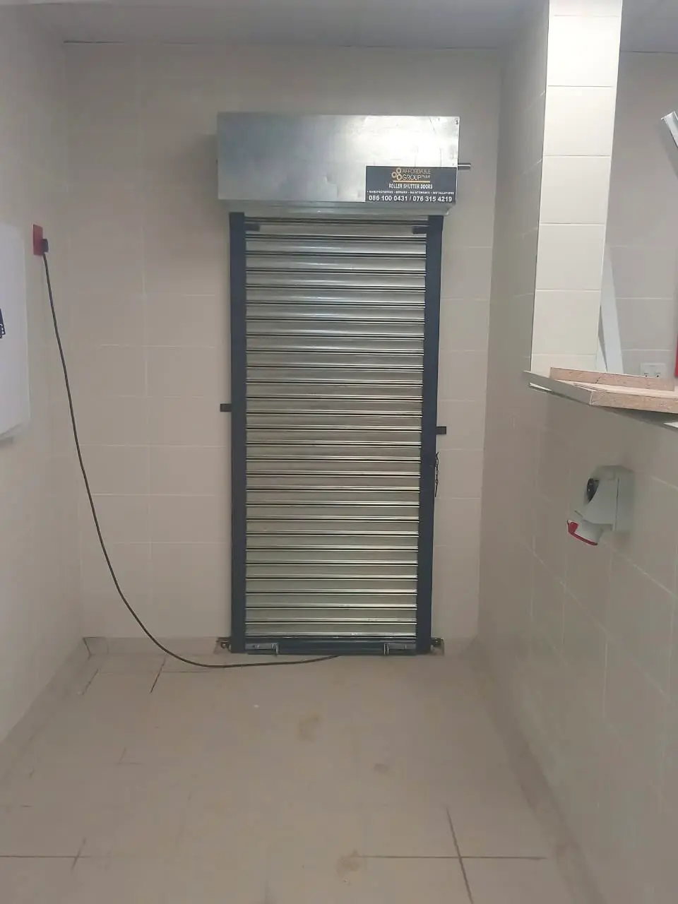 Narrow roller shutter door inside a tiled commercial room