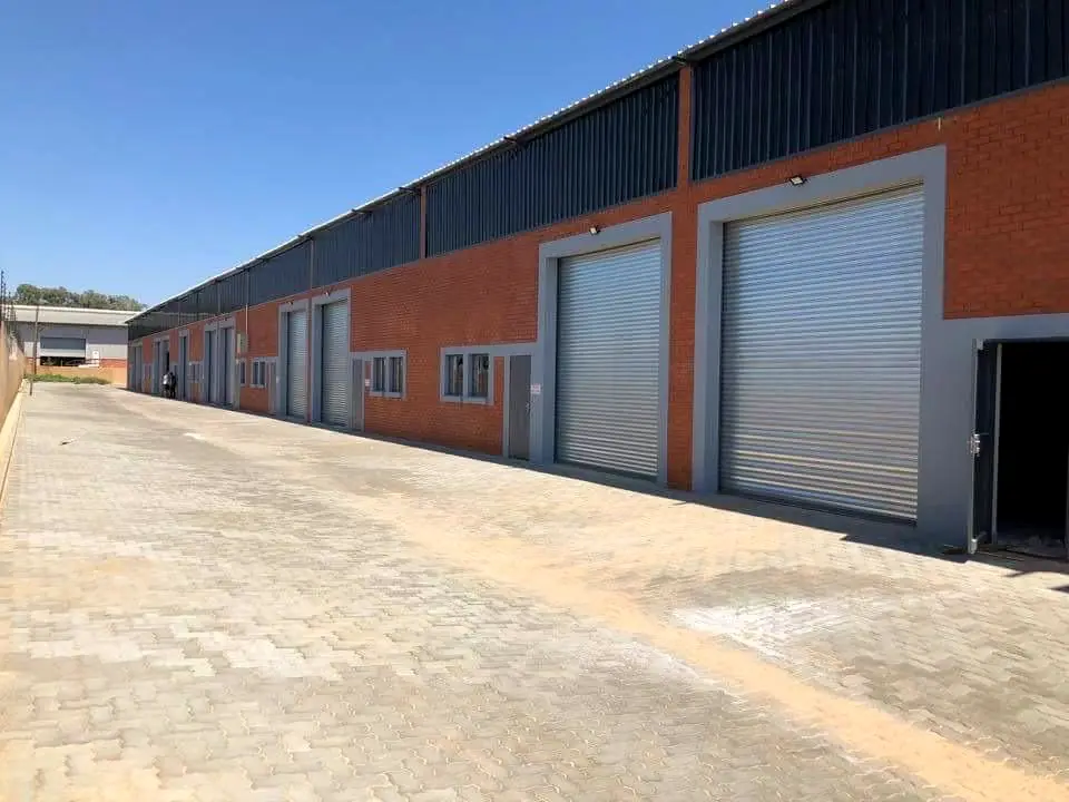 Row of grey industrial roller doors on a new face-brick warehouse park