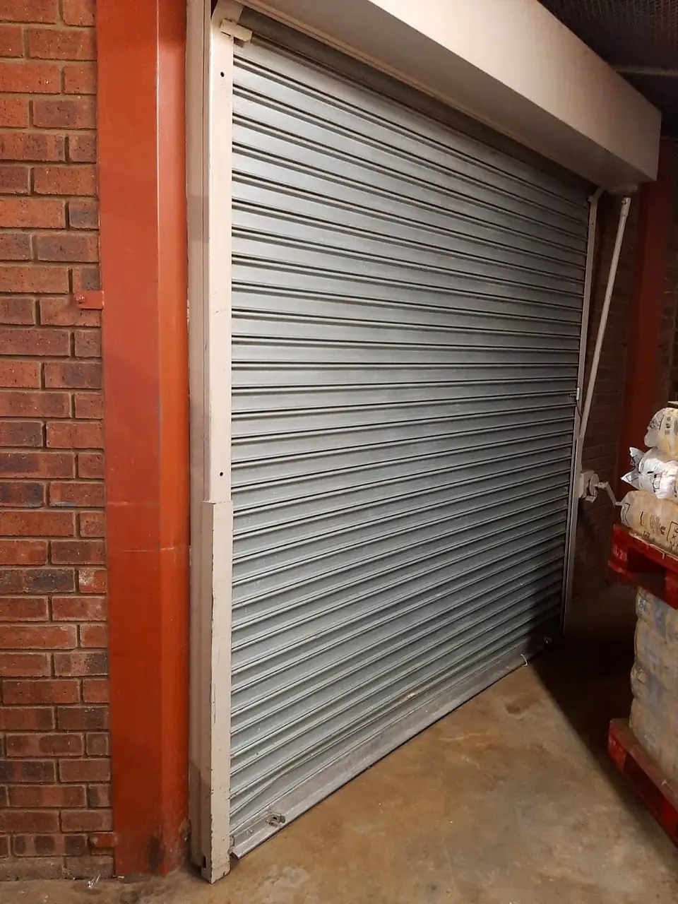 Galvanised roller shutter in a red steel frame