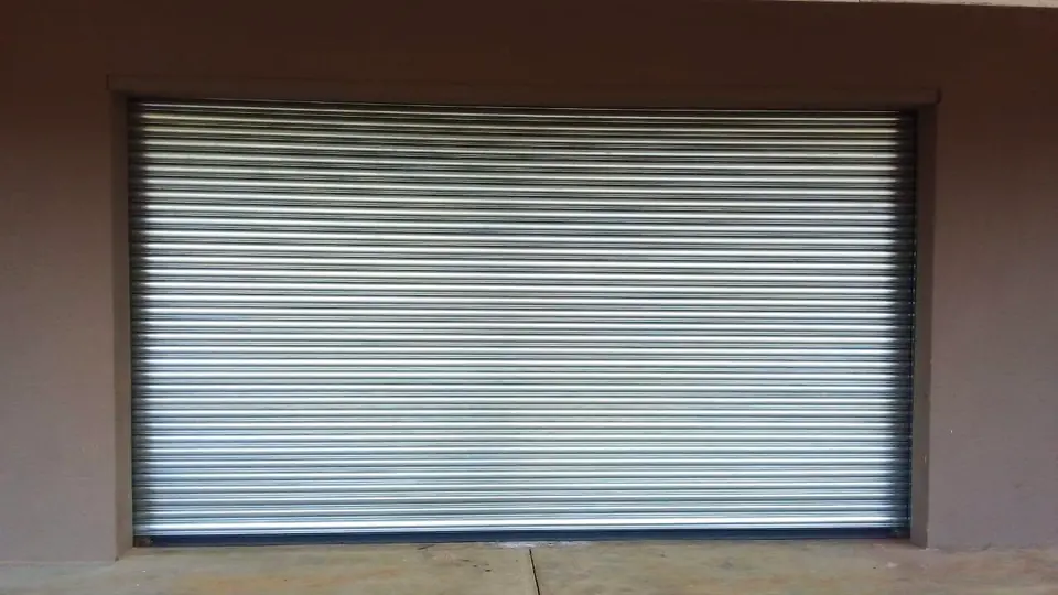 Galvanised roller shutter in a rendered wall opening