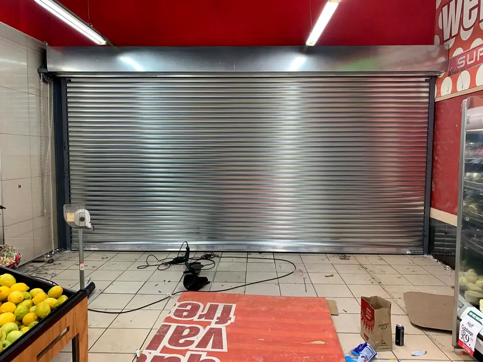 Wide galvanised roller shutter installed inside a retail store